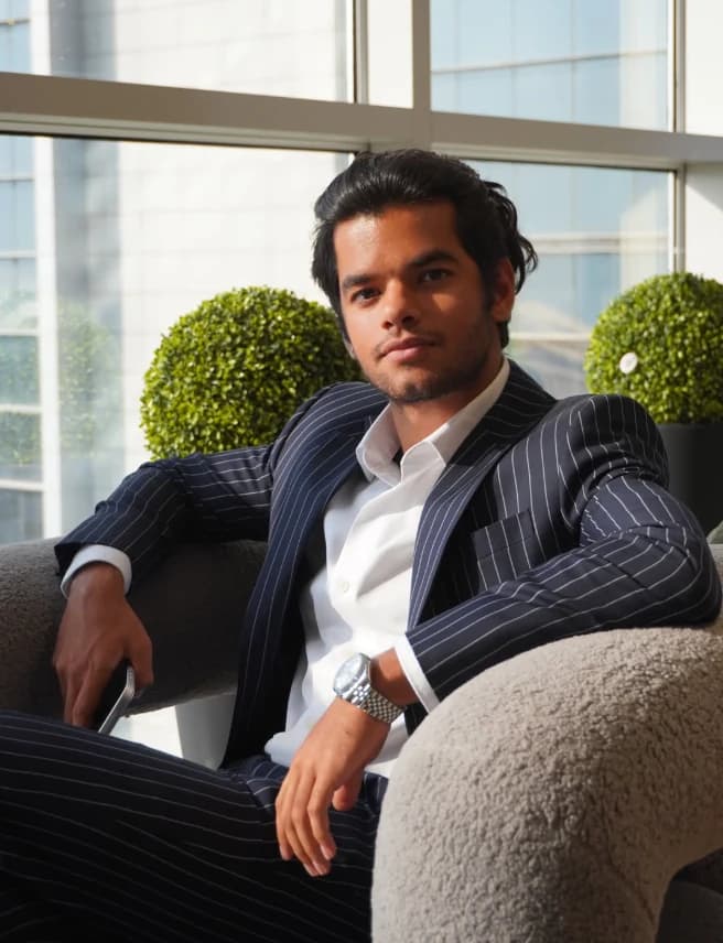 Jai Bachani in a pinstripe suit, seated by the window of his Dubai office